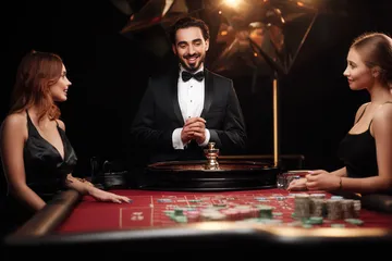 GOOB111 Live Casino — Join thrilling real-dealer tables A professional dealer in a tuxedo greeting players at the roulette table, symbolizing the authentic live casino feel at GOOB111.