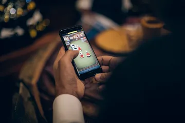 A man celebrating a winning moment on his laptop while gaming symbols float around him, capturing the excitement of GOOB111 games.